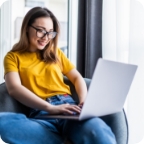Woman smiles while using a laptop.